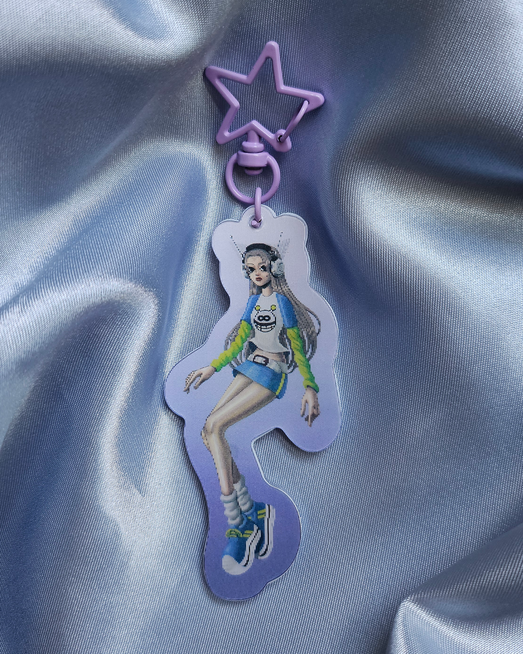 Keychain with lenticular effect of a girl dressed in Y2k Fashion that transitions to a girl dressed in Medieval garb. The clasp is light purple and in a star shape.